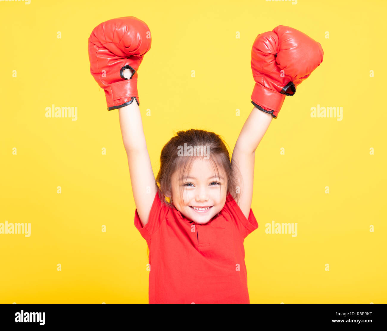 Felice bambina con red guantoni da pugilato su sfondo giallo Foto Stock