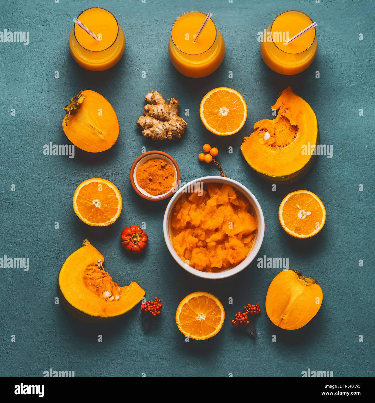 Un sano frullato di zucca con colore arancio ingredienti : persimmon , Arancia frutti, lo zenzero e la curcuma in polvere su sfondo blu, vista dall'alto, piatto laici. Foto Stock