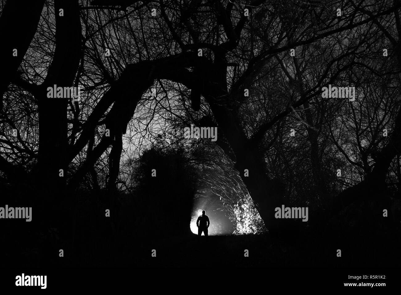 Un uomo si erge stagliano contro una luce su un sentiero tranquillo di notte in Swillington,West Yorkshire Foto Stock