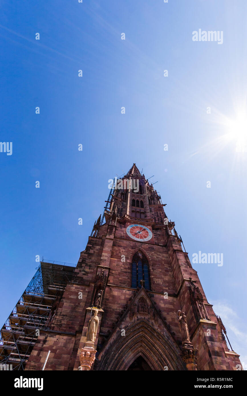 Basso angolo vista di Friburgo la cattedrale di Munster in una giornata di sole sotto il cielo blu chiaro. Freiburg im Breisgau, Baden-Württemberg, Germania Foto Stock