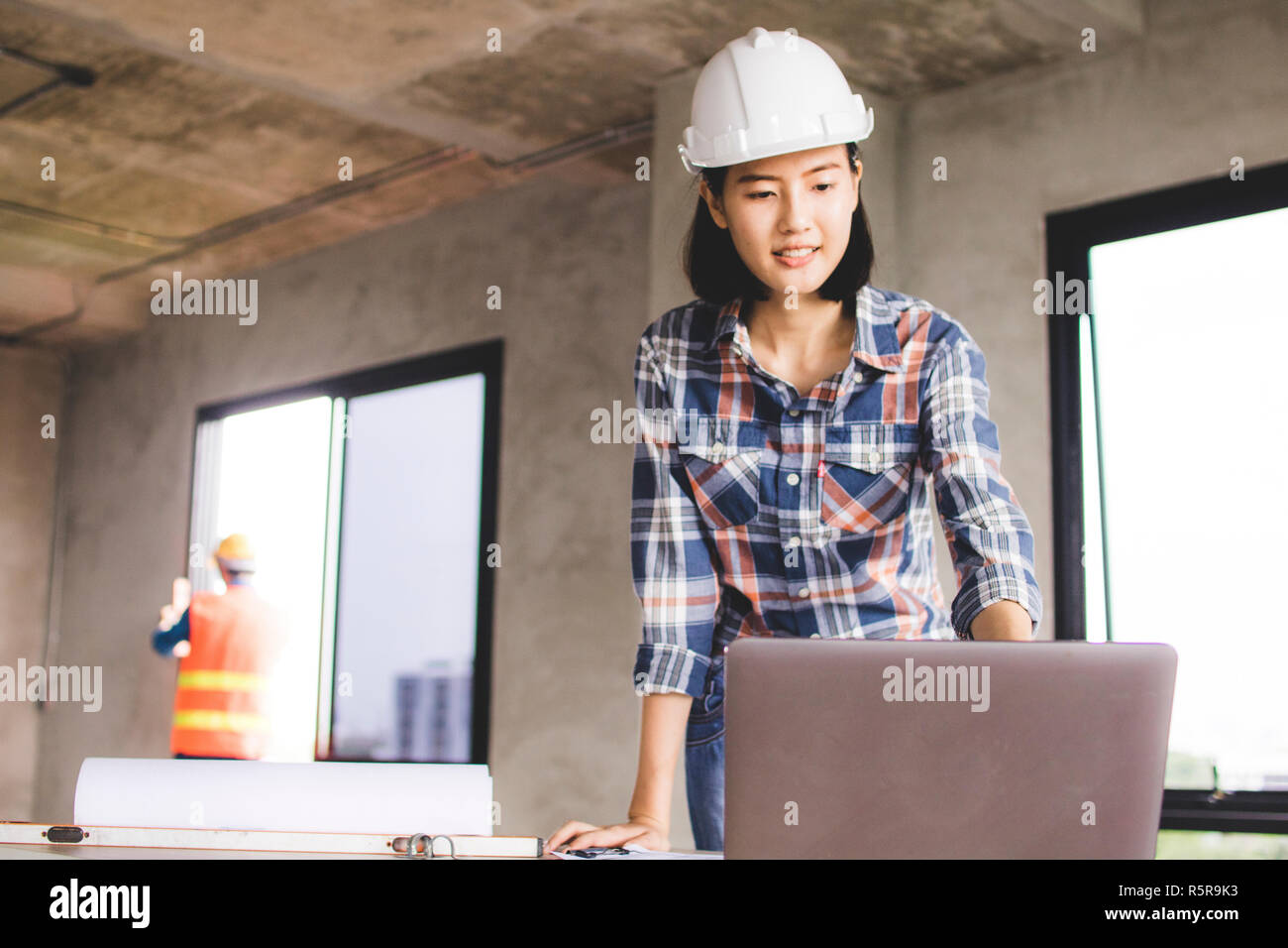 Donna ingegnere guardare il computer circa progredendo e costruzione di ruspare su blueprint nel sito di lavoro Foto Stock