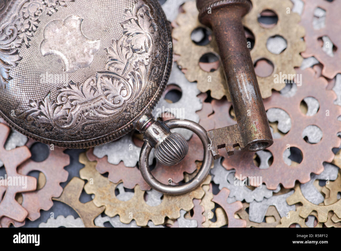 Panta Rhei concetto: antico orologio da tasca, vecchia chiave vintage e ora gli ingranaggi metallici sulla pietra naturale dello sfondo. Foto Stock