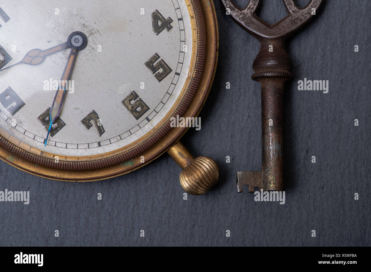 Panta Rhei concetto: antico orologio da tasca e chiave vintage sulla pietra naturale dello sfondo. Foto Stock