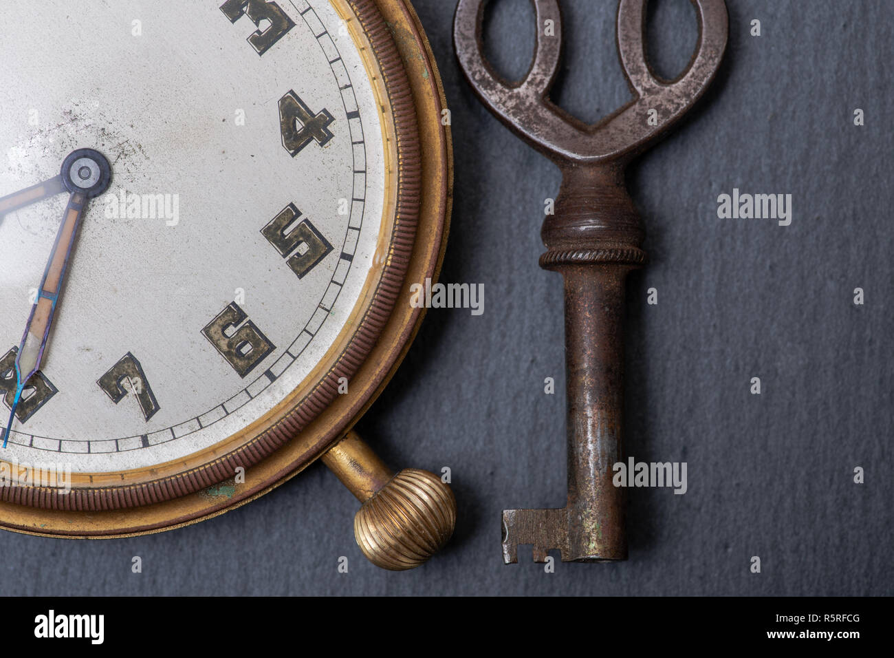 Panta Rhei concetto: antico orologio da tasca e chiave vintage sulla pietra naturale dello sfondo. Foto Stock