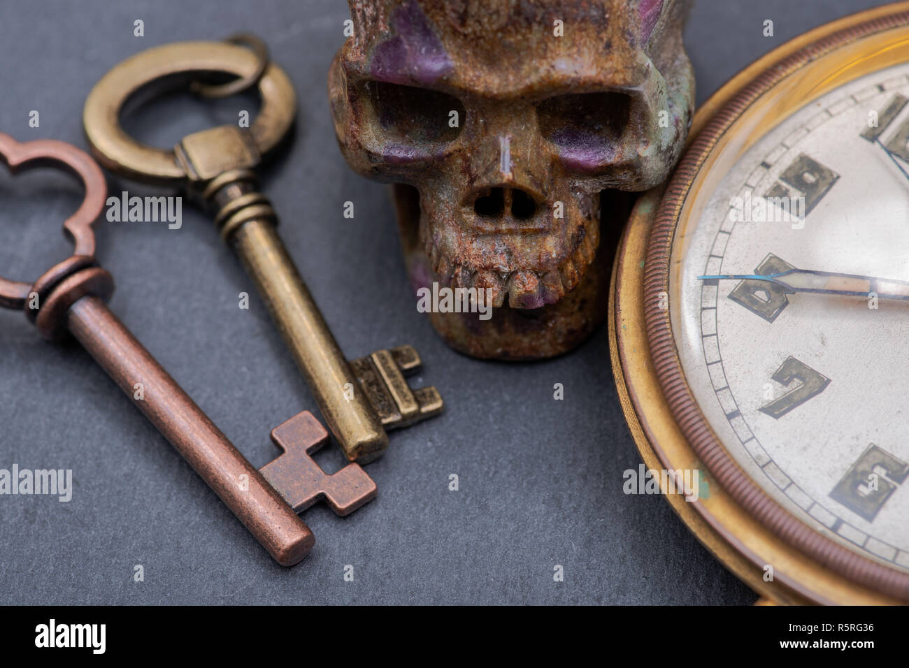 Panta Rhei concetto: antico orologio da tasca, old vintage tasti in metallo e pietra scolpita sul cranio di pietra naturale dello sfondo. Foto Stock