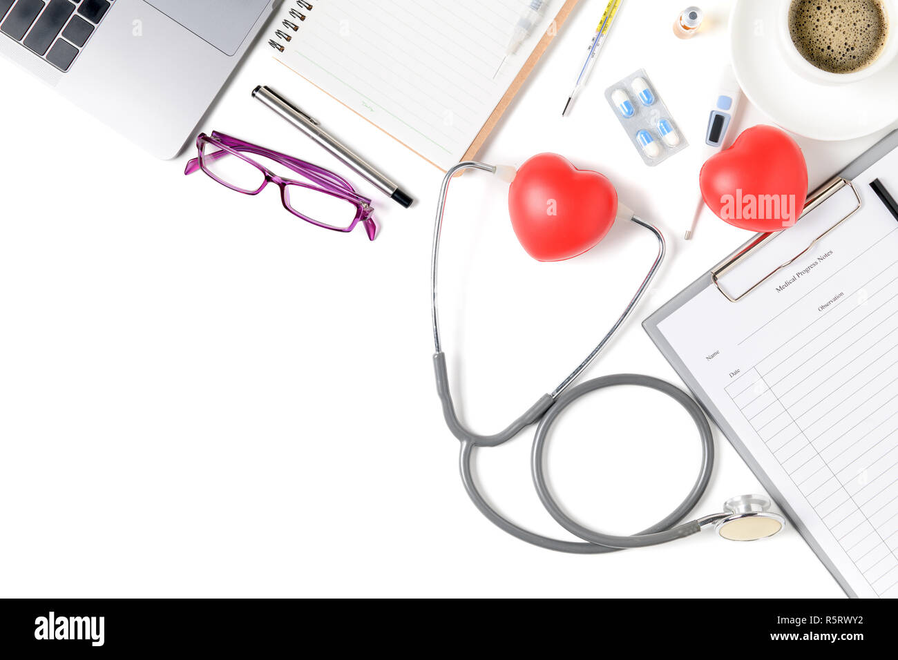 Vista superiore del medico scrivania con uno stetoscopio e cuore rosso, caffè e laptop. Vista da sopra con copia spazio, laici piana. Foto Stock
