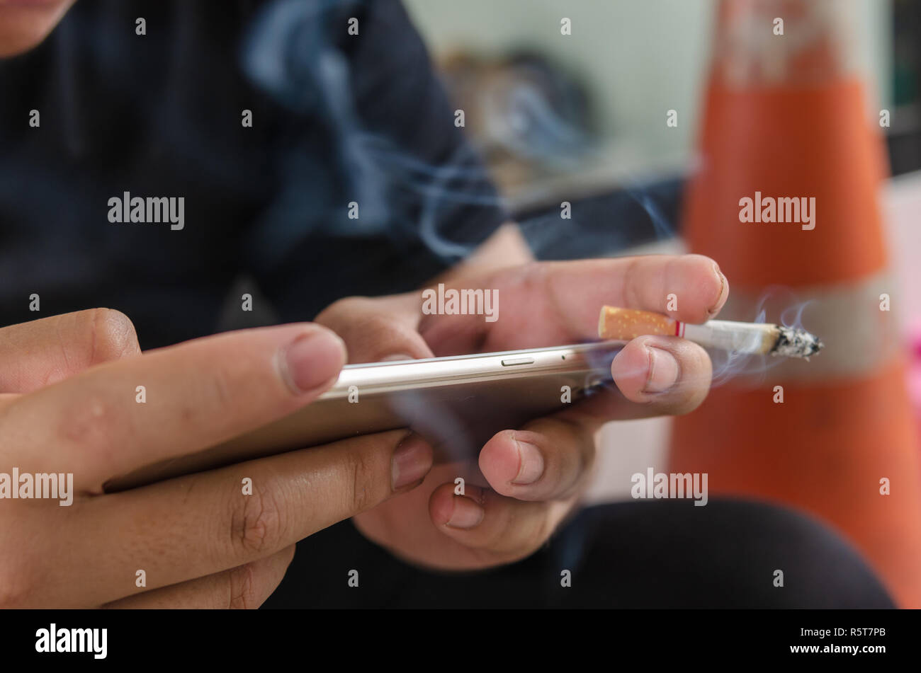 Man mano azienda utilizzando smart phone e fumare cigarett. Foto Stock