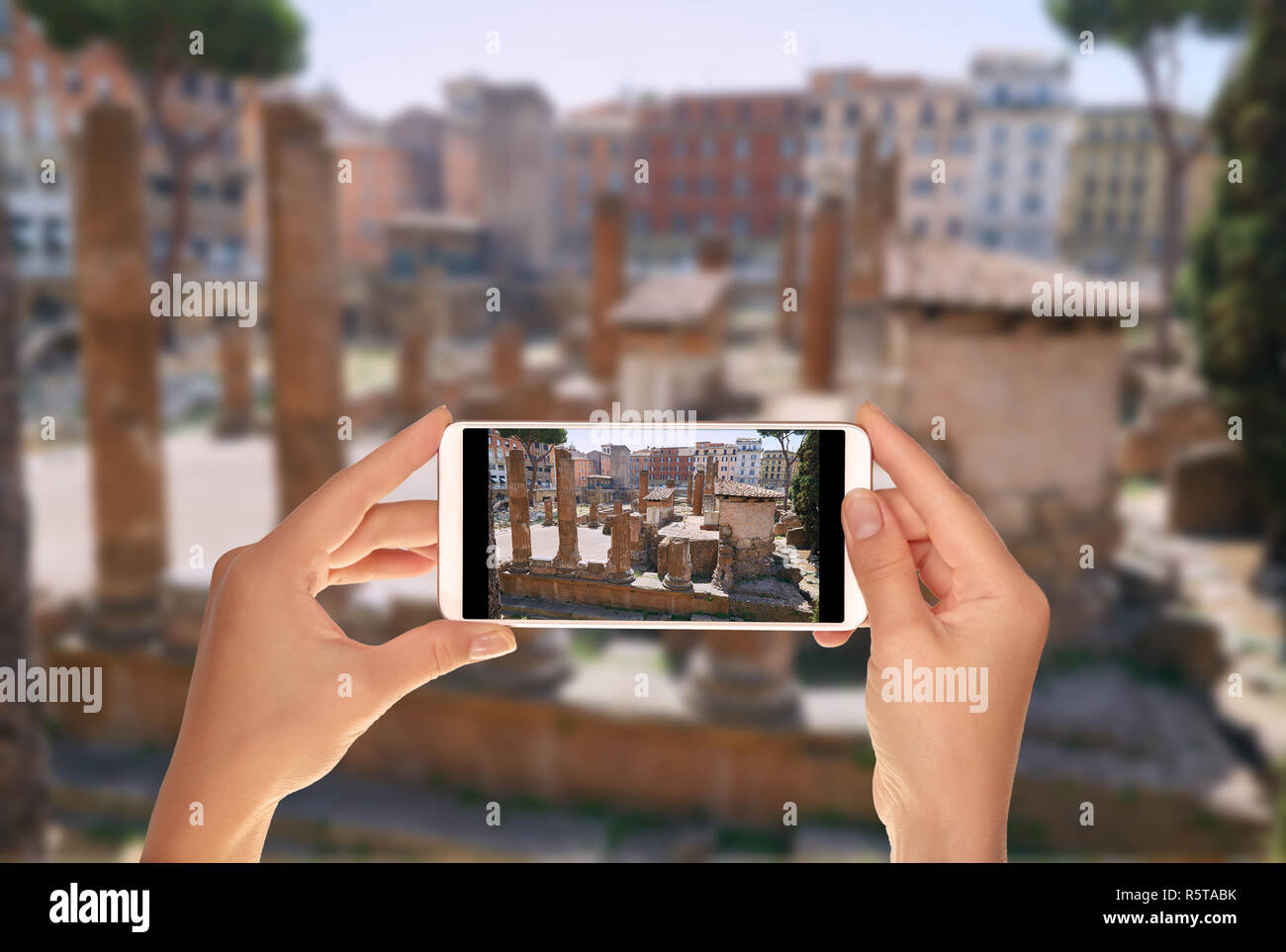 Un turista è di scattare una foto di antiche rovine sulla piazza della Torre argentino in Italia a Roma su un telefono cellulare Foto Stock