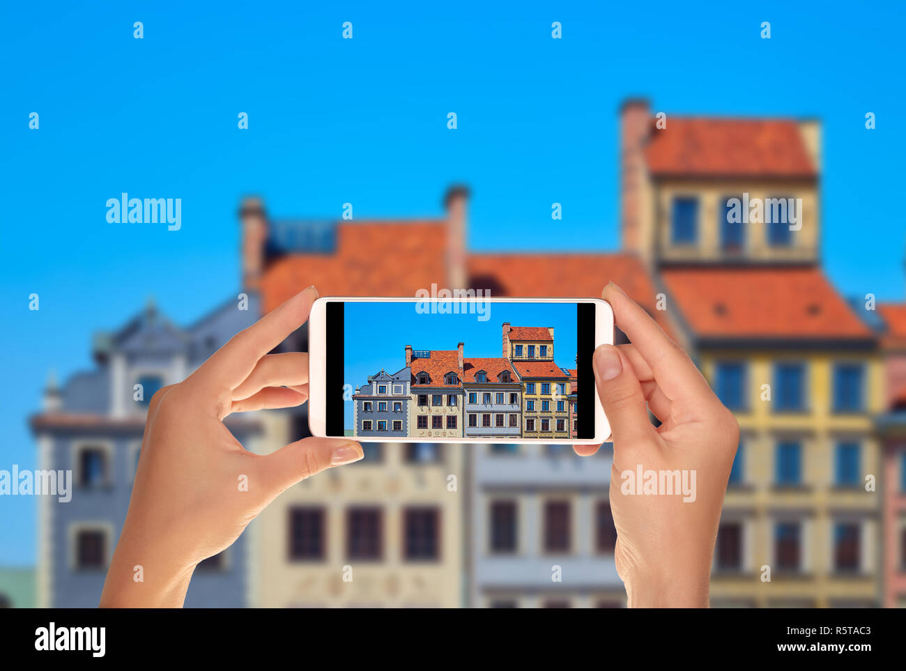 Un turista è di scattare una foto di belle case colorate sulla piazza del mercato a Varsavia in Polonia su un telefono cellulare Foto Stock