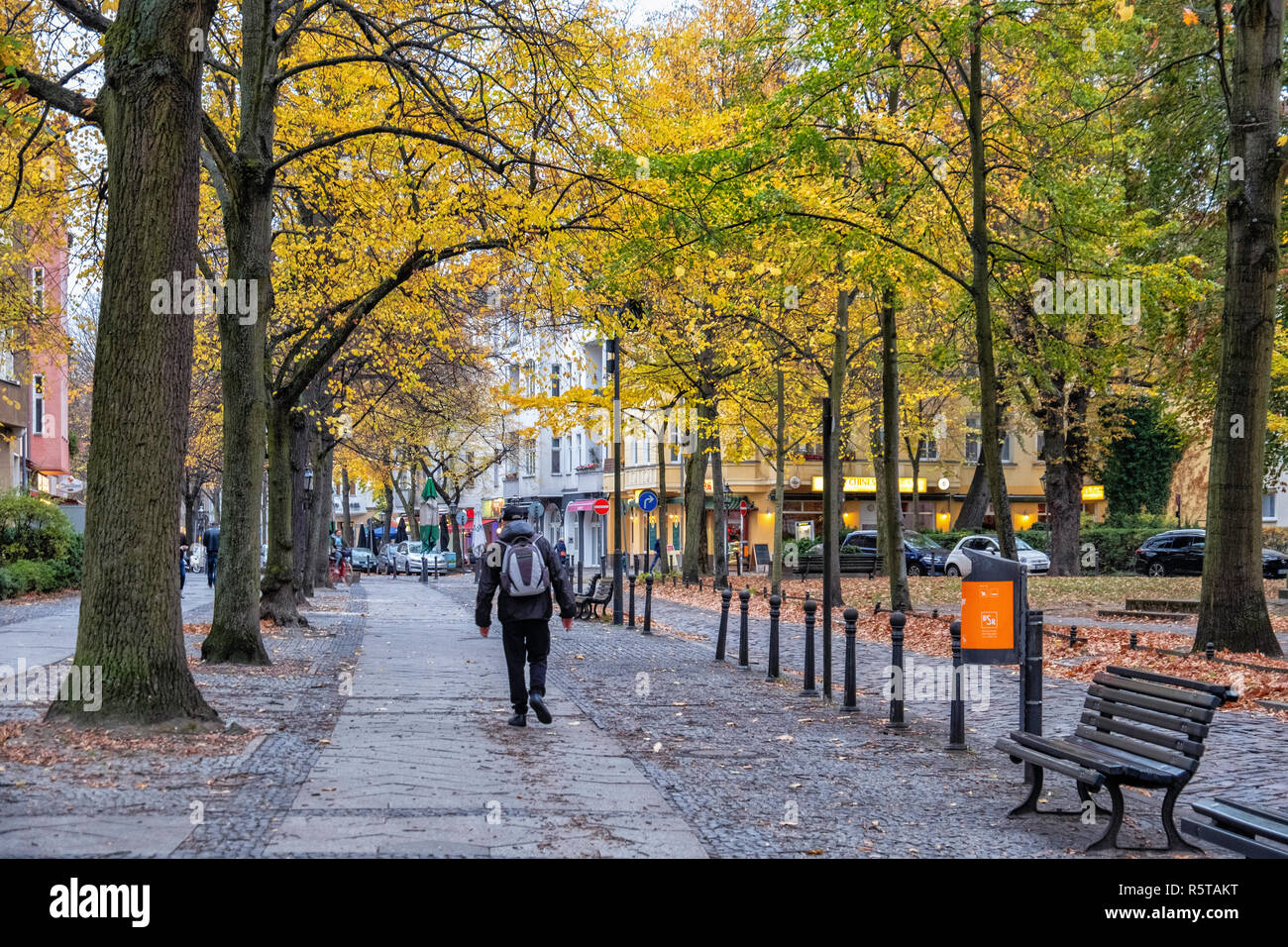 Berlino, vista strada storica vecchia edifici di appartamenti e negozi in Alt-Tegel street in autunno & uomo con zaino Foto Stock
