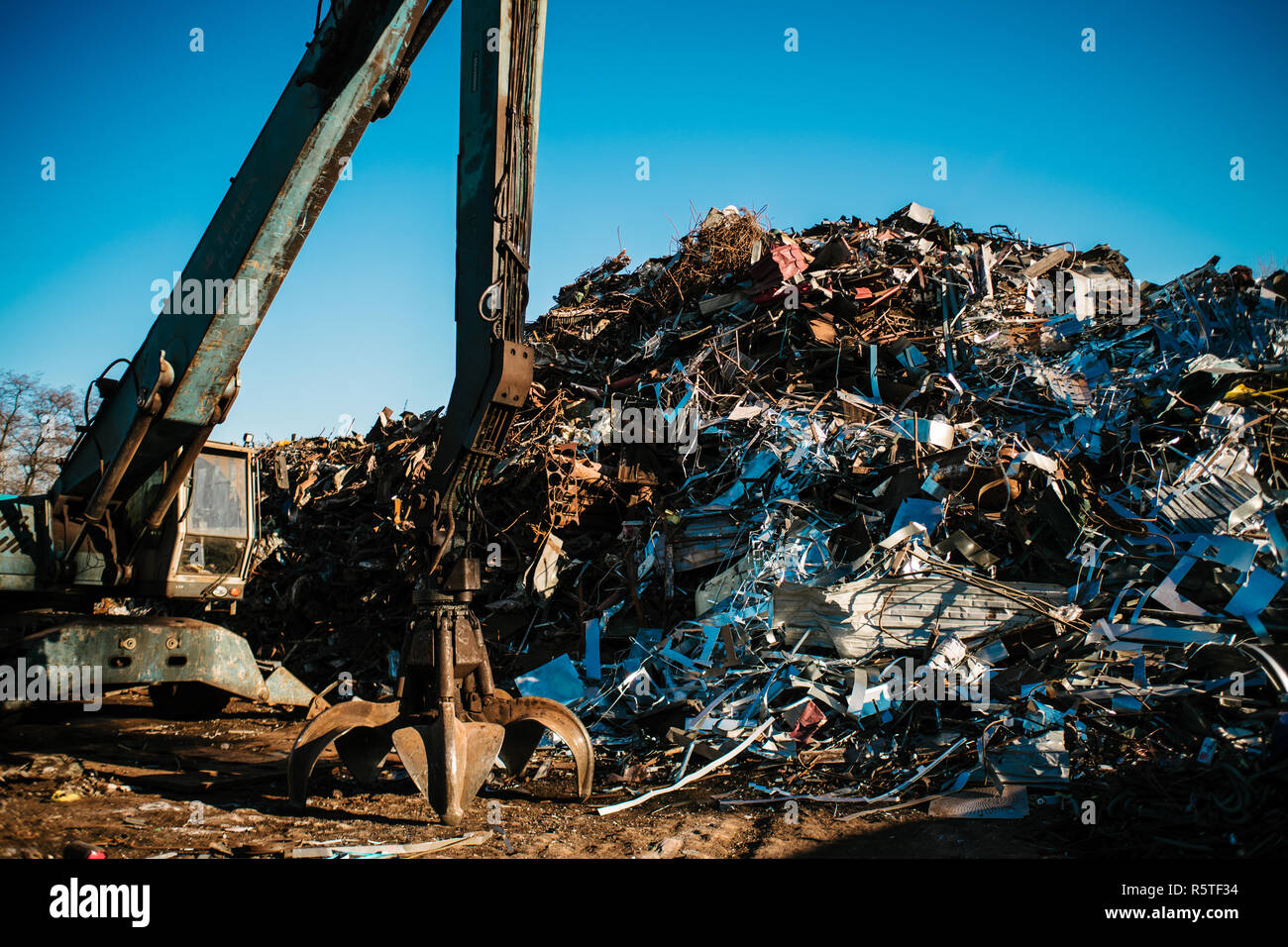 Stazione di riciclaggio. Dump di metallo con gru di lavoro e il profondo blu del cielo Foto Stock