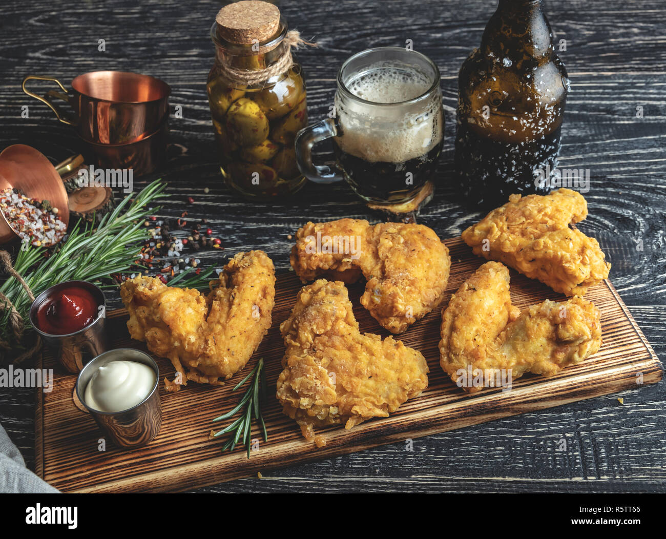 Alette di pollo fritte in pastella, rosso e salsa bianca su di una superficie scura Foto Stock