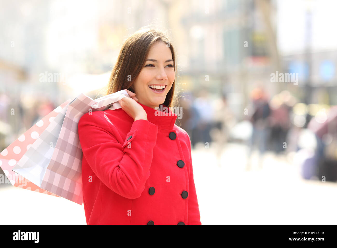 Happy shopper in passeggiate invernali e tenendo le borse della spesa in strada Foto Stock