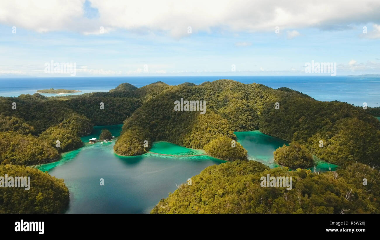 Vista aerea: spiaggia, isola tropicale, Baia Mare e laguna, Siargao. Paesaggio tropicale hill, nuvole e montagne rocce con la foresta pluviale. Acque azzurre della laguna. Paesaggio Shore Bay. Concetto di viaggio. Foto Stock