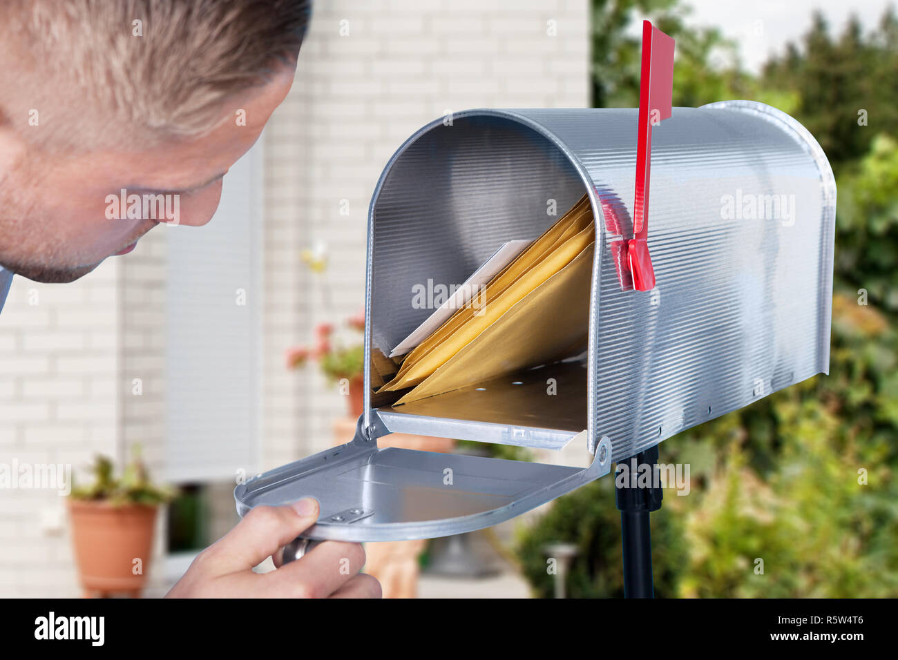 Uomo di aprire la sua mailbox per rimuovere la posta Foto Stock