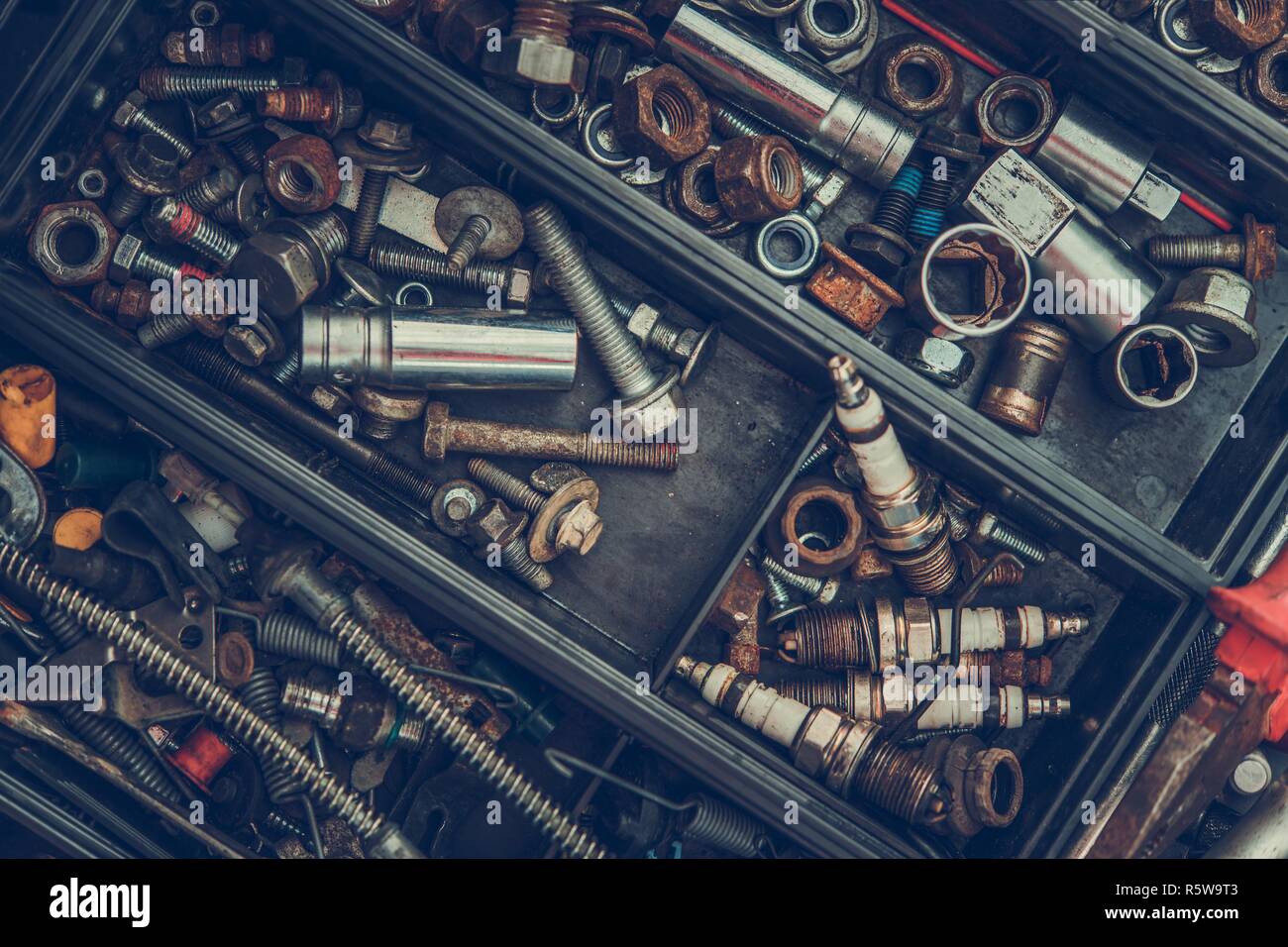 Garage cassetta degli attrezzi con molte viti, bulloni e auto a candele di accensione. Foto Stock