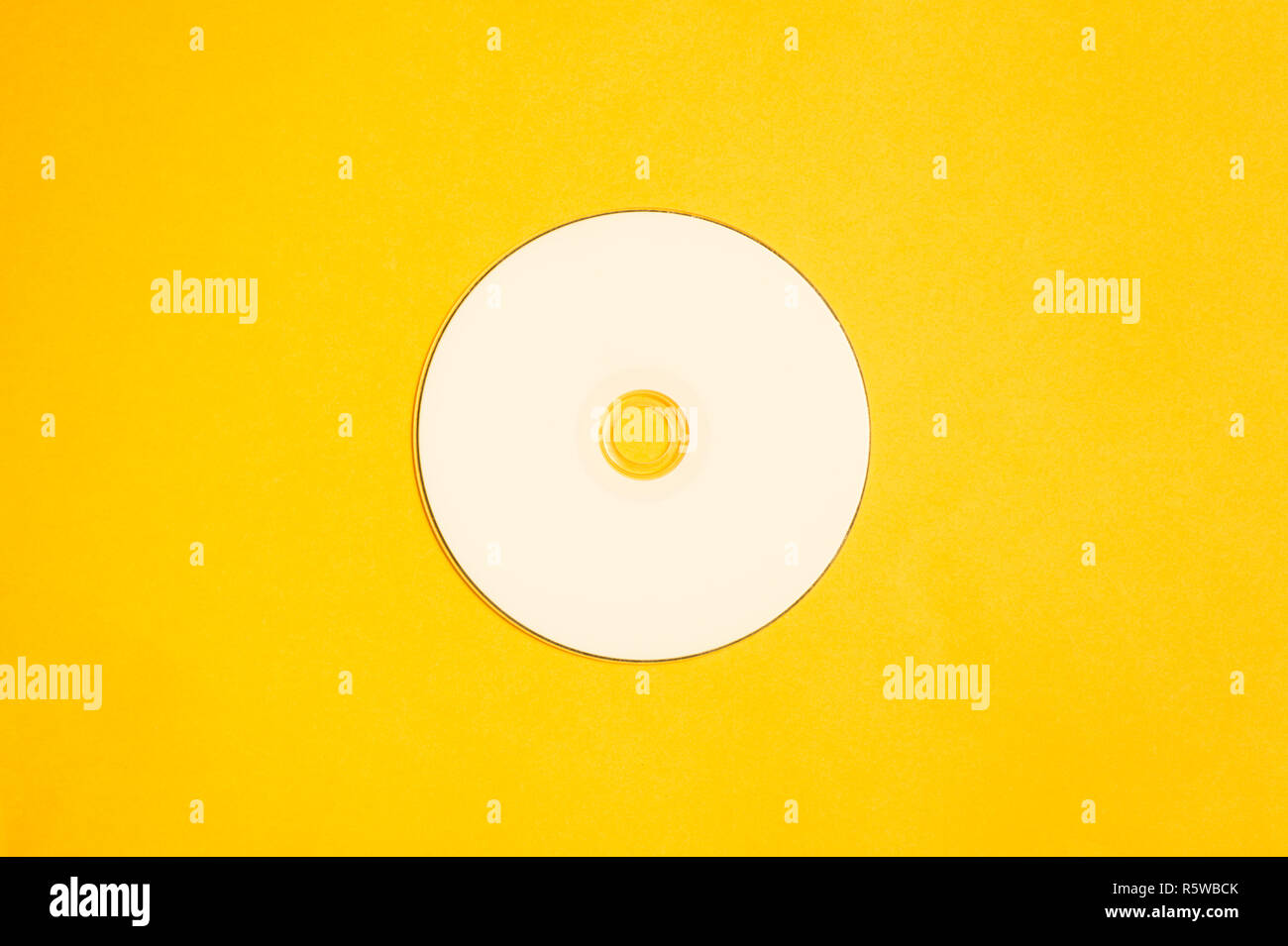 White compact disc su sfondo giallo Foto Stock