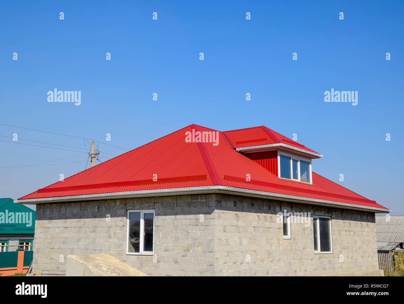 Rosso tetto ondulato. Casa del blocco di scorie. Casa con finestre in  plastica e il tetto del foglio ondulato Foto stock - Alamy