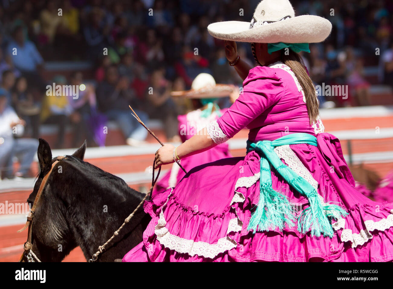 Un messicano escaramuza ragazza saluta il pubblico prima che inizi la prestazione di charreada Foto Stock