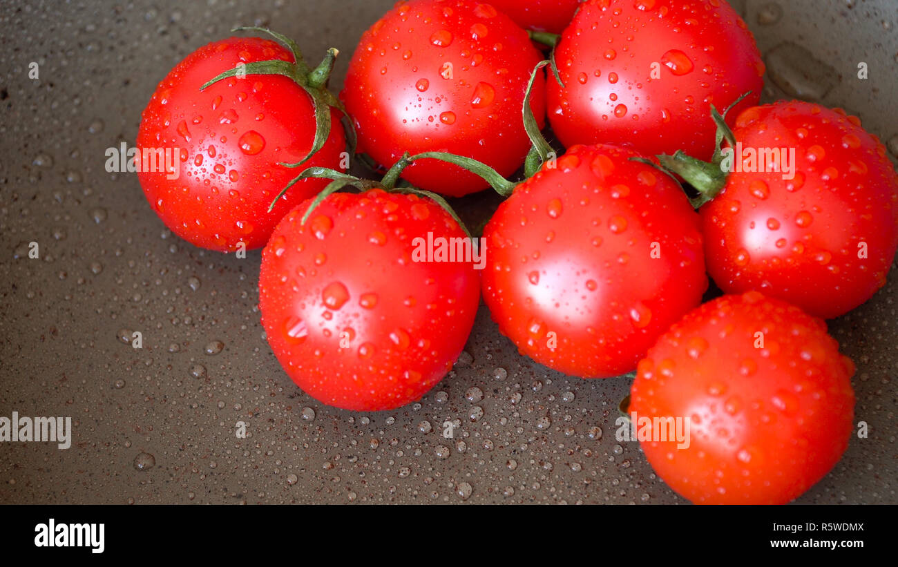 Cumulo di ripe succosi pomodorini coperti da gocce di acqua. Foto Stock