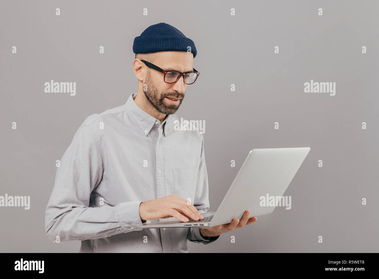 Professional Developer Download file, chat online in reti sociali, bloggs e surfes pagine web internet indossa maglietta formale, si erge contro il GRE Foto Stock
