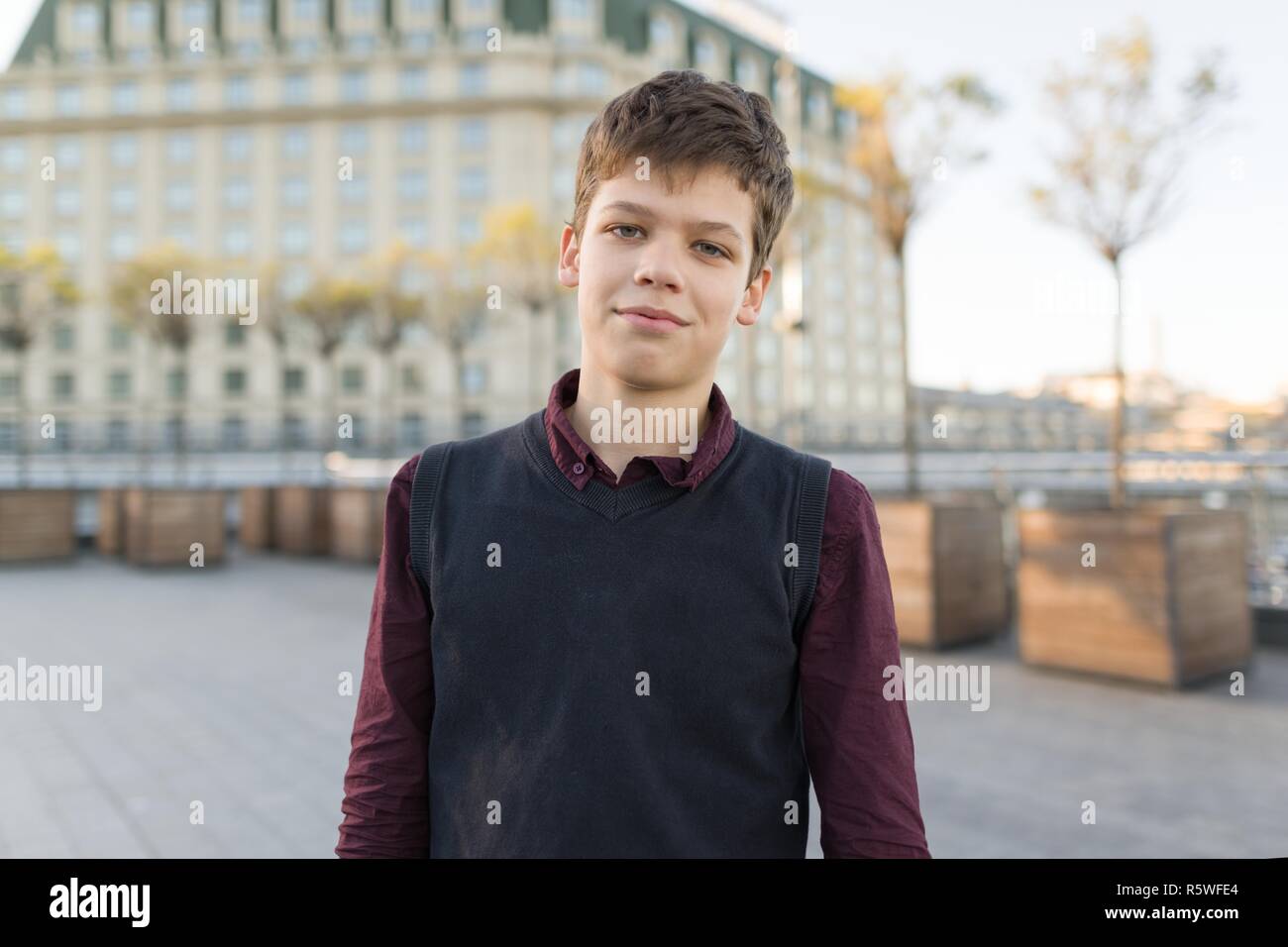 Outdoor ritratto di sorridente ragazzo adolescente 14, 15 anni. Sullo sfondo della città, ora d'oro Foto Stock