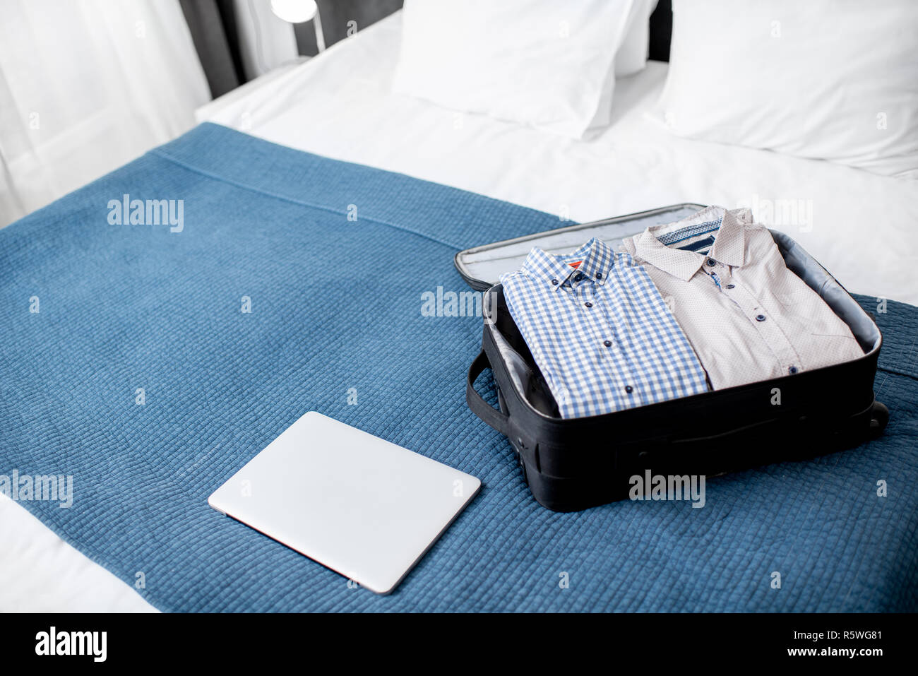 Valigia piena di vestiti con il computer portatile sul letto della camera  in hotel o in camera da letto. Viaggio di lavoro concept Foto stock - Alamy