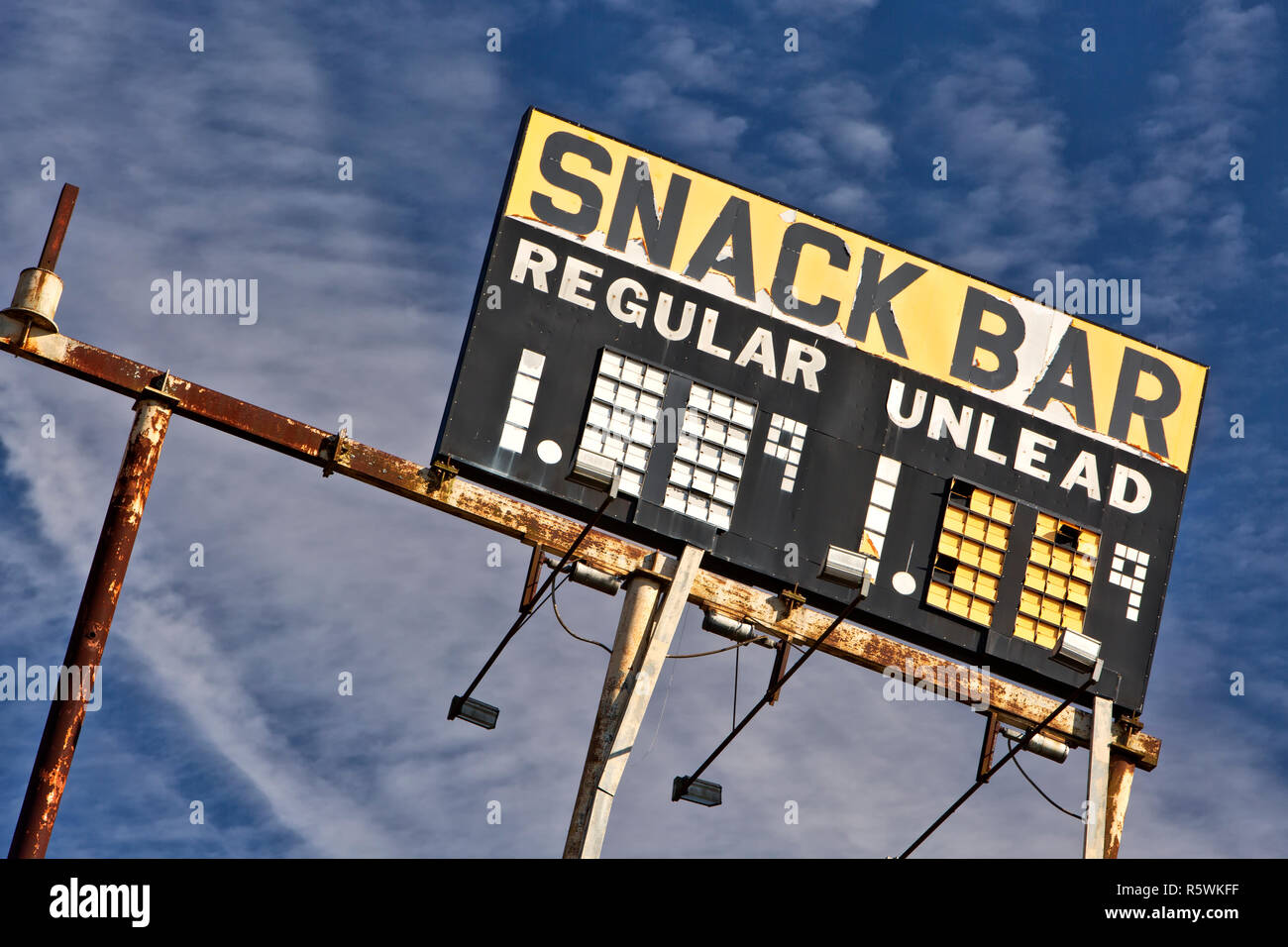 Elevata di Gas Vintage segno stazione "nack bar - regolari & Unlead' BENZINA, contro un sparsi in cielo blu. Foto Stock