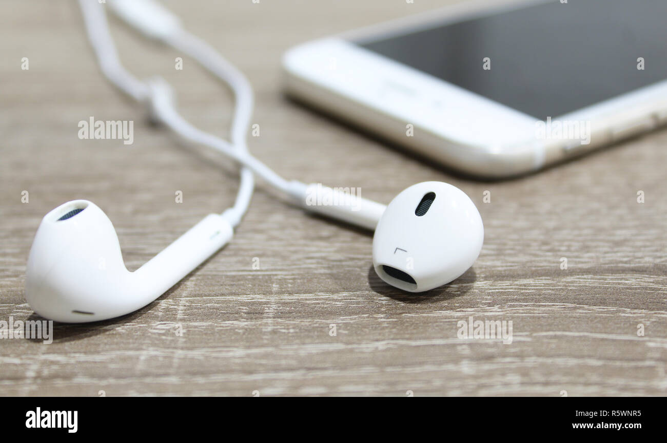 Gli auricolari bianco su una superficie di legno e lo smartphone in  background. Auricolari piccoli close up Foto stock - Alamy