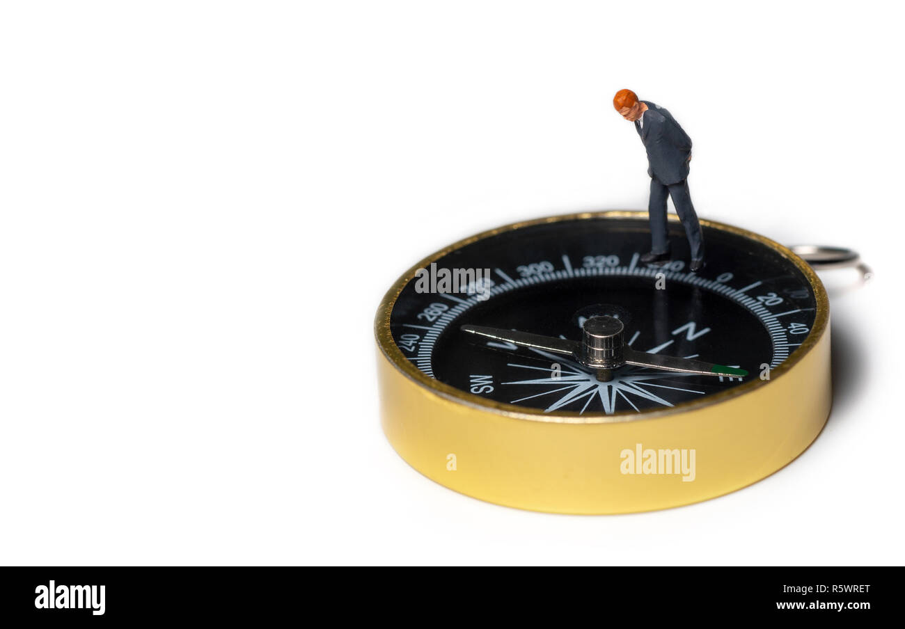 Figura in miniatura imprenditore nel buio tuta blu permanente sulla bussola dorata per trovare il modo di successo di affari e finanziario Foto Stock