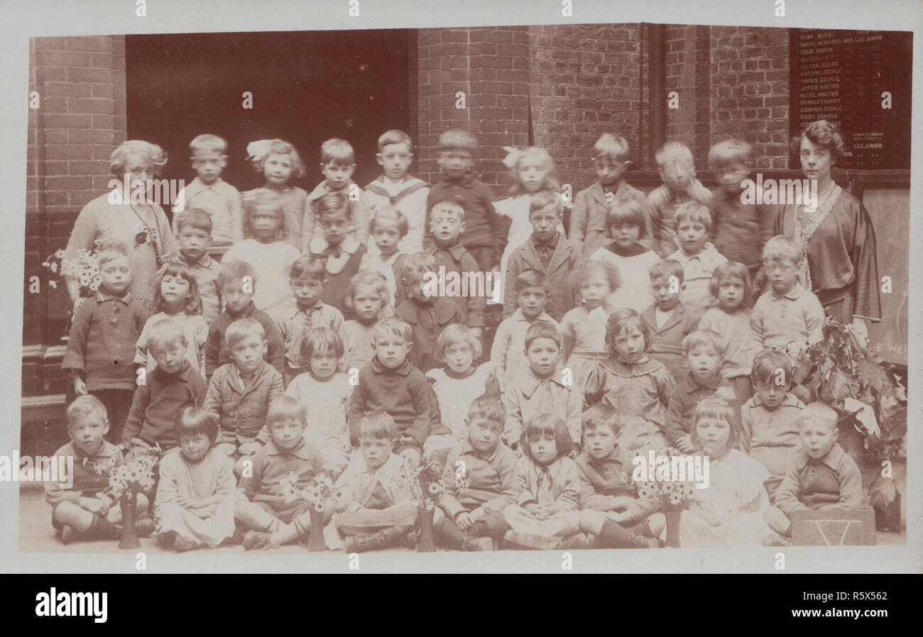 * Vintage Cartolina fotografica che mostra un gruppo di Edwardian i bambini delle scuole e i loro insegnanti. Foto Stock