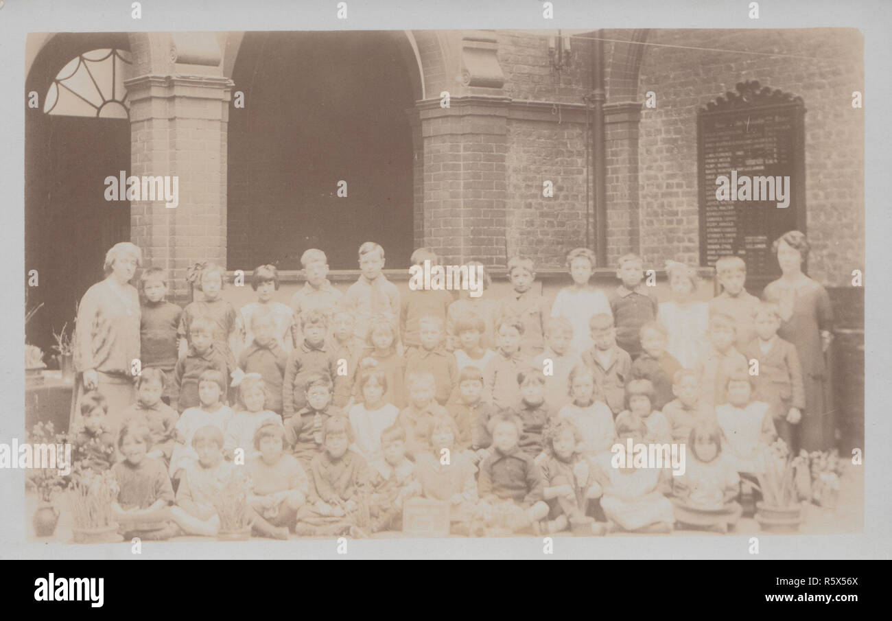 * Vintage Cartolina fotografica che mostra un gruppo di Edwardian i bambini delle scuole e i loro insegnanti. Foto Stock