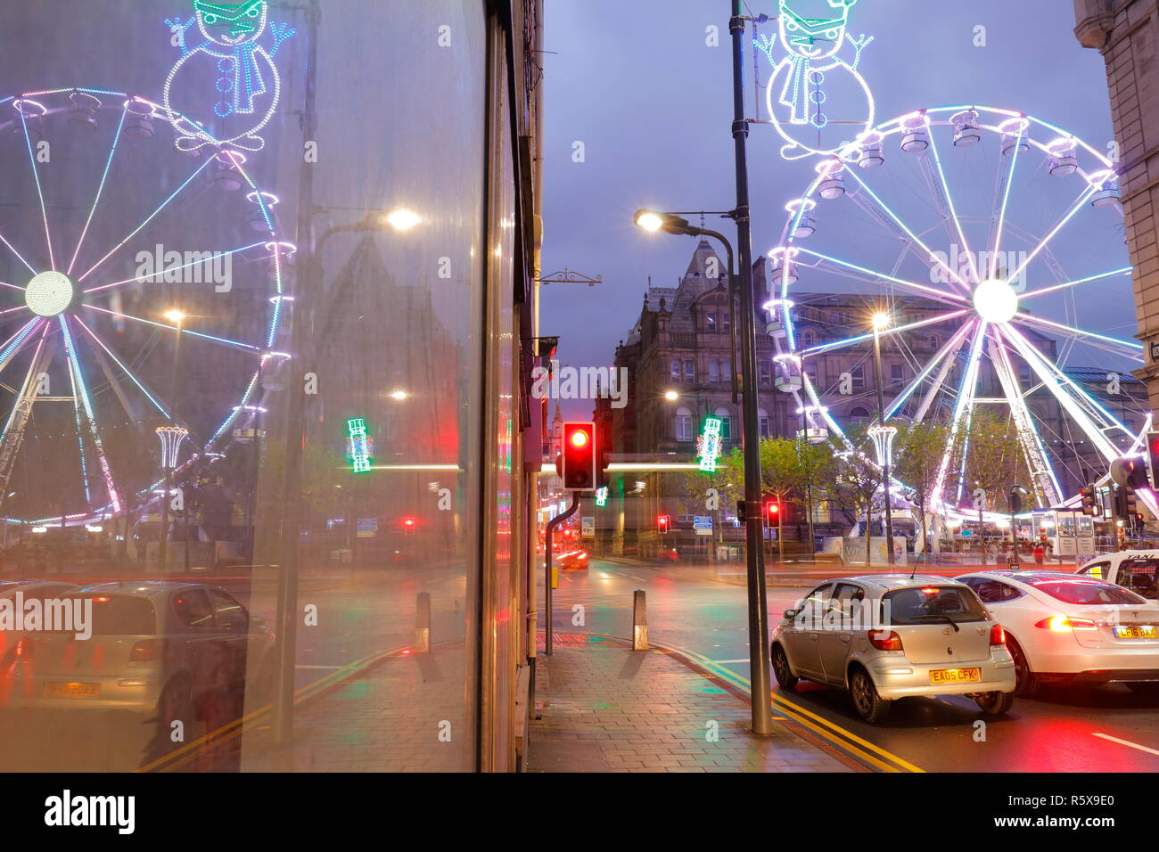 Riflessioni attraverso una finestra, della ruota grande attrazione turistica in Leeds City Centre di notte. Foto Stock