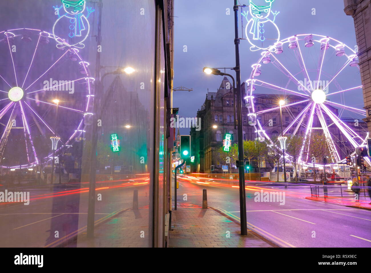 Riflessioni attraverso una finestra, della ruota grande attrazione turistica in Leeds City Centre di notte. Foto Stock