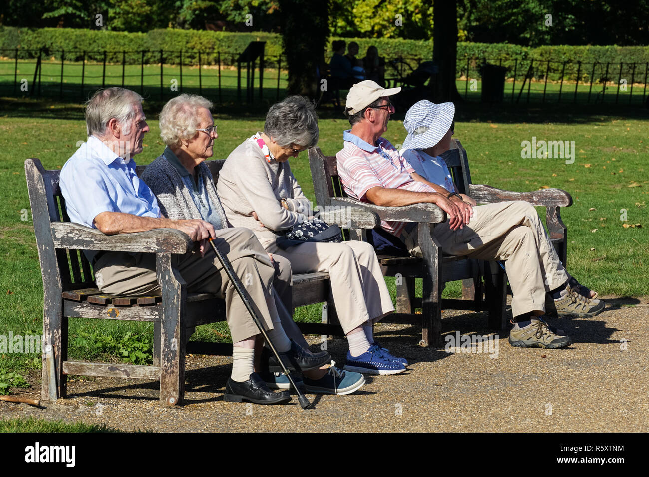 Gli anziani seduti su un banco di lavoro in una giornata di sole nel parco Higginson, Marlow, Buckinghamshire, Inghilterra Regno Unito Regno Unito Foto Stock