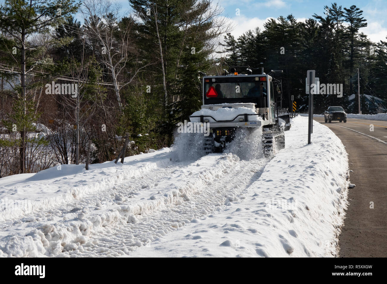 Un Prinoth Husky snow toelettatore guidando lungo il marciapiede, parte di una motoslitta trail, in speculatore, NY USA nel Parco Adirondacks. Foto Stock