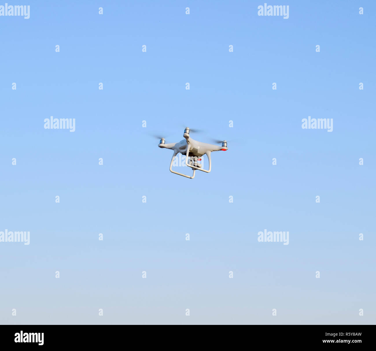 Drone bianco contro il blu del cielo della sera. Volo Multicopter. Foto Stock