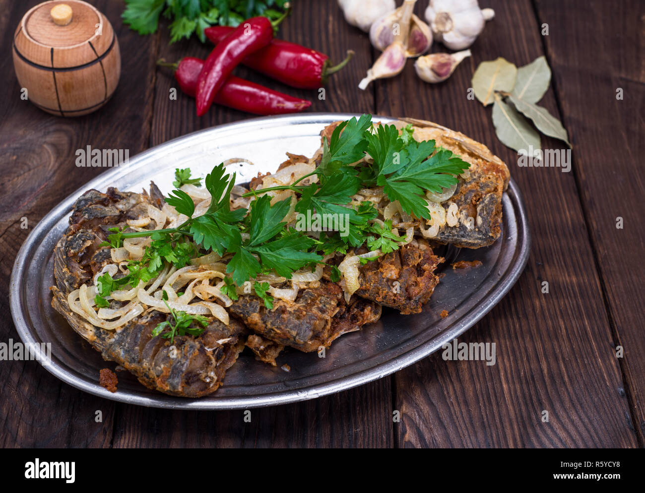 Pesce fritto carassio con cipolle su una piastra di ferro Foto Stock