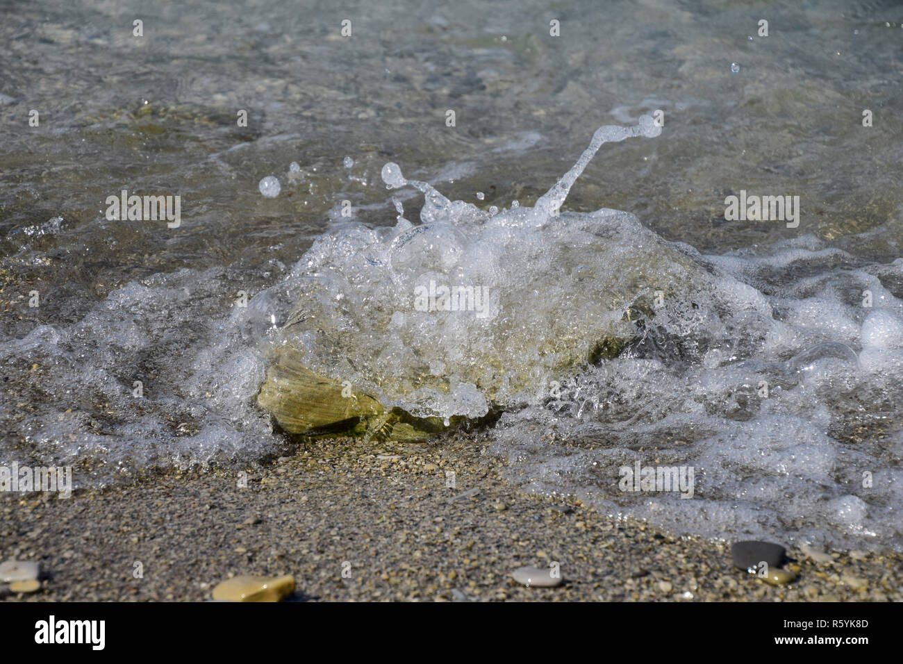 Le onde del mare eseguito a terra, la formazione di bolle e il rivestimento in pietra Foto Stock