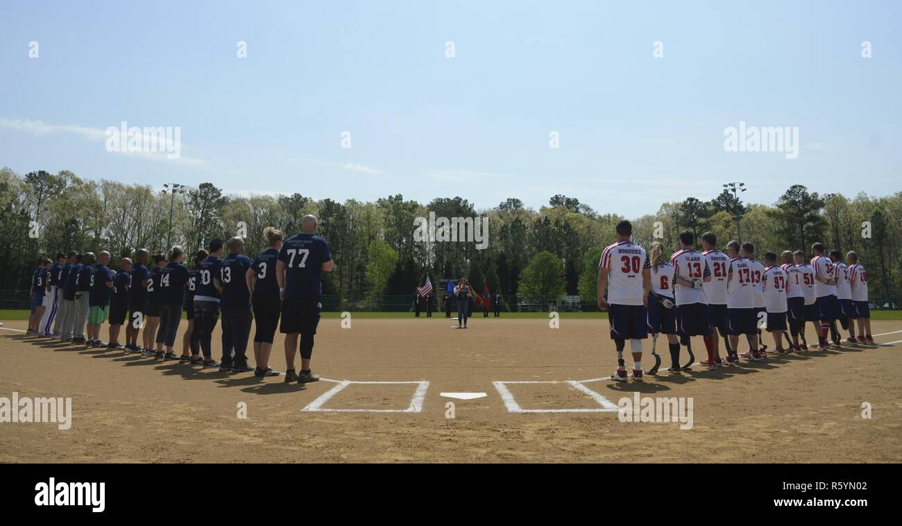 Il guerriero ferito amputato Softball Team stand con il Newport News la polizia e i vigili del fuoco durante la riproduzione di un inno nazionale presso il gioco WWAST in Newport News, Va., 15 aprile 2017. Il WWAST è composta di veterani e active-servizio i membri che hanno perso gli arti mentre si serve dei militari poiché 9/11. Foto Stock