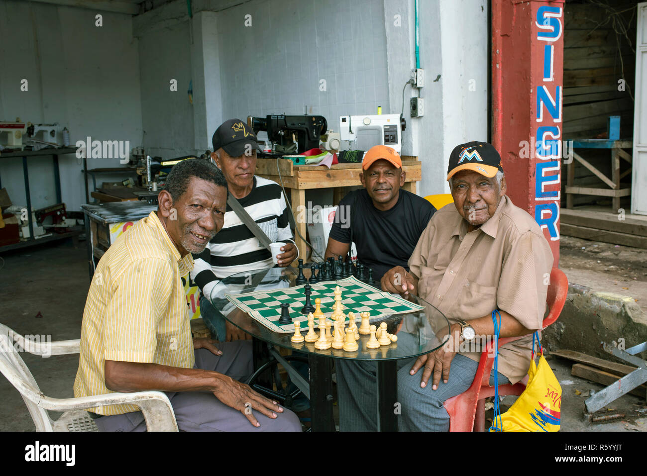 Un gruppo locale di uomini giocare a scacchi al di fuori della macchina per cucire negozio di riparazione, vicino mercato Bazurto. Cartagena de Indias, Colombia. Ott 2018 Foto Stock