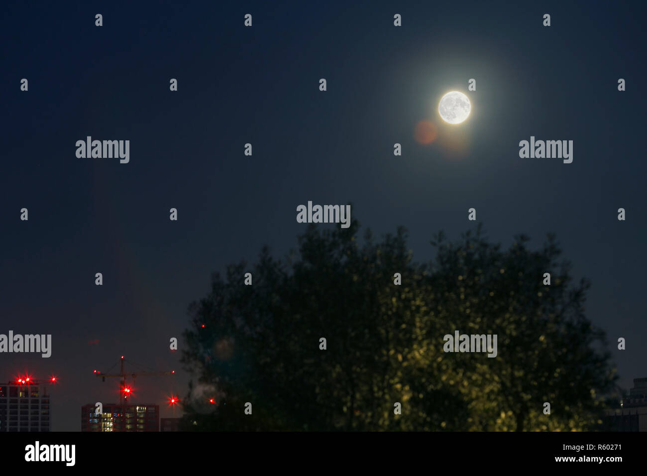 Luna piena sopra la città di Docklands a Canary Wharf. Londra, Inghilterra. Foto Stock