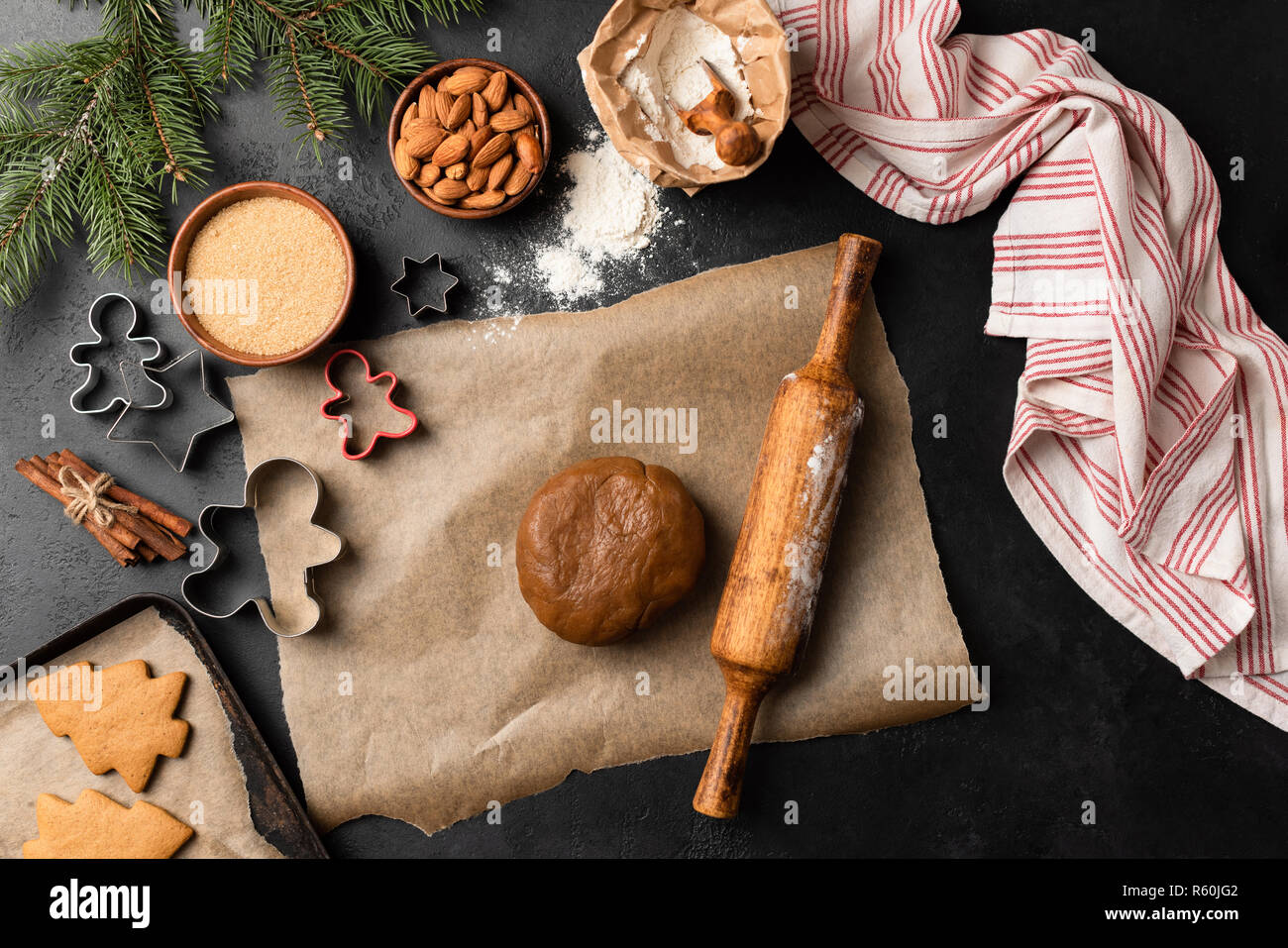 Gingerbread cookie cottura. Vacanze di Natale cottura sul calcestruzzo nero lo sfondo. Vista superiore Foto Stock