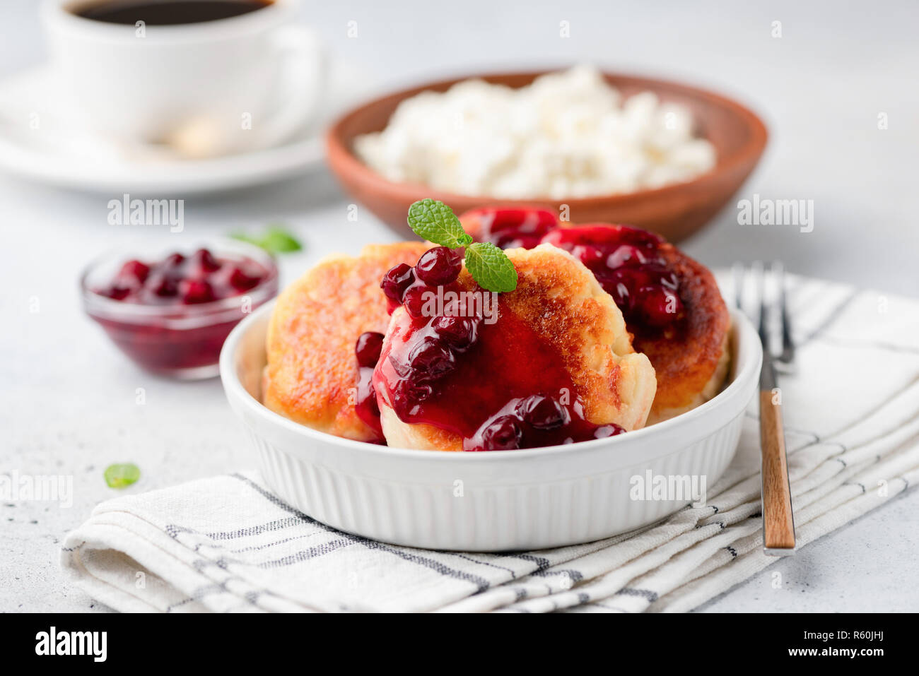 Syrniki o ricotta frittelle con marmellata di mirtilli. Russo, Ucraino cucina. Formaggio fritto polpette con salsa dolce Foto Stock