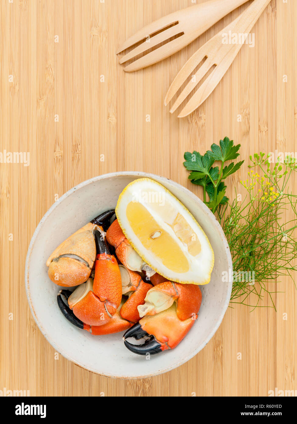 Freschi cotti al vapore granchi rossi gamba nella vaschetta . Gamberi rossi gamba con ingredienti. Vaporizzato granchi rossi gamba con erbe aromatiche finocchio ,prezzemolo,rosmarino,limone e menta con la forcella della boscosa scheda di taglio. Foto Stock