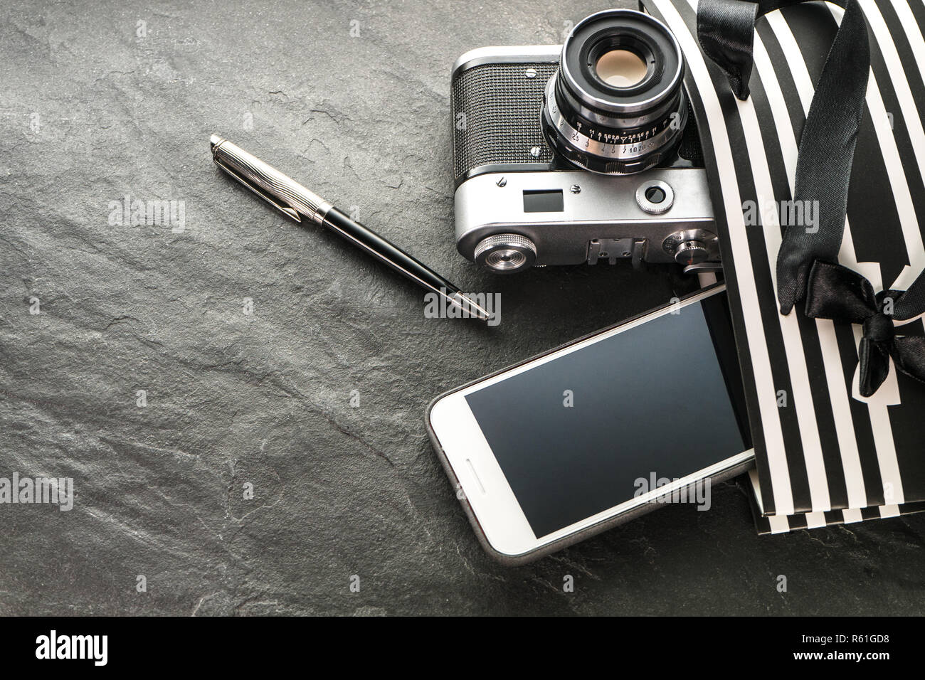 Telefono, fotocamera, penna in un pacchetto nero con strisce bianche con il pulsante destro Foto Stock
