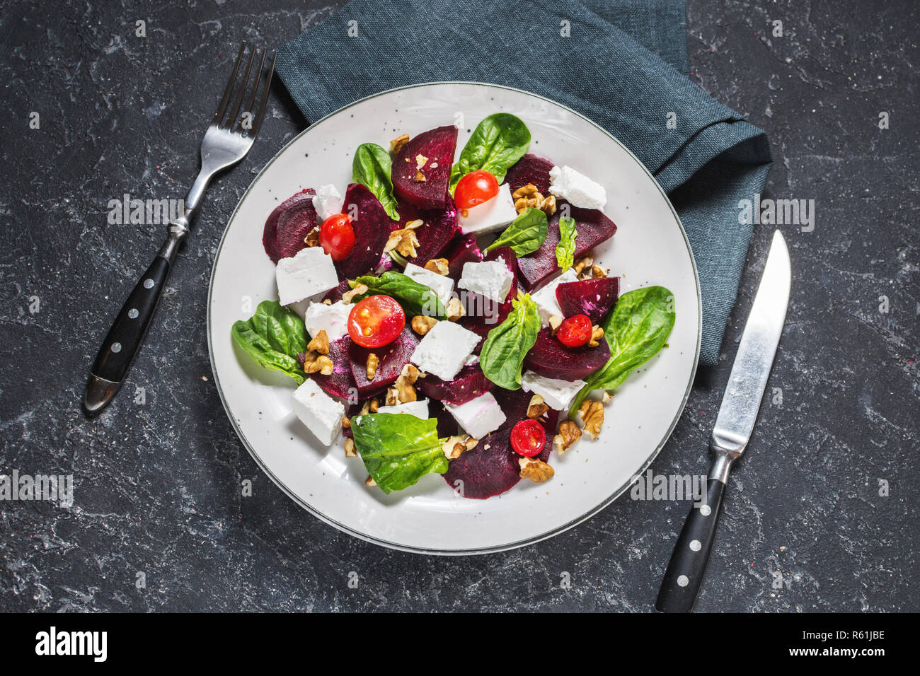 Il piatto con una insalata di feta, barbabietole, pomodorini e noci su un sfondo di pietra. Foto Stock
