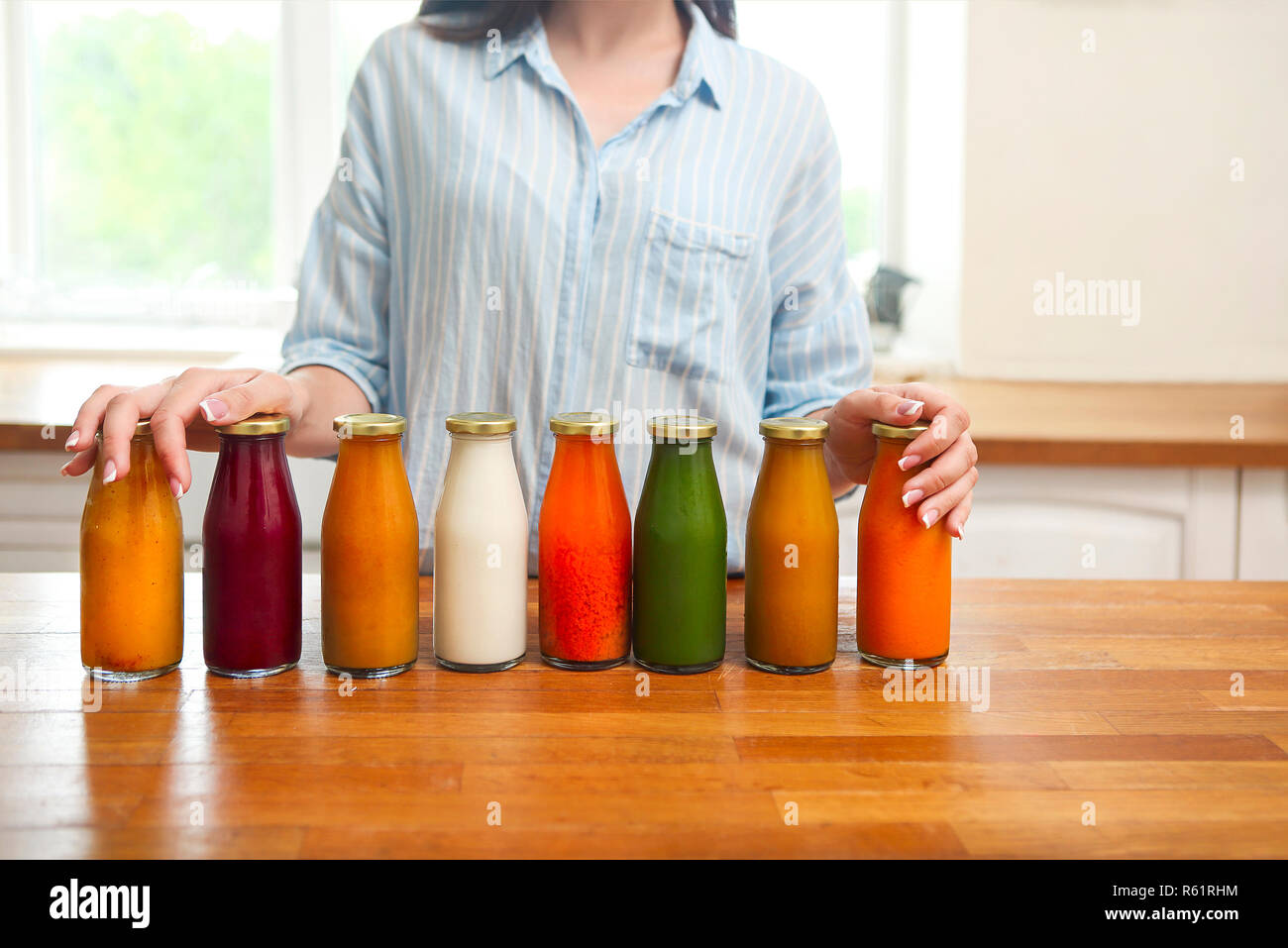 La dieta nutrizione con detox succo. Donna sana in posa con succo fresco di bottiglie di detox frullato. Primo piano della felice fit bella ragazza in cucina Foto Stock