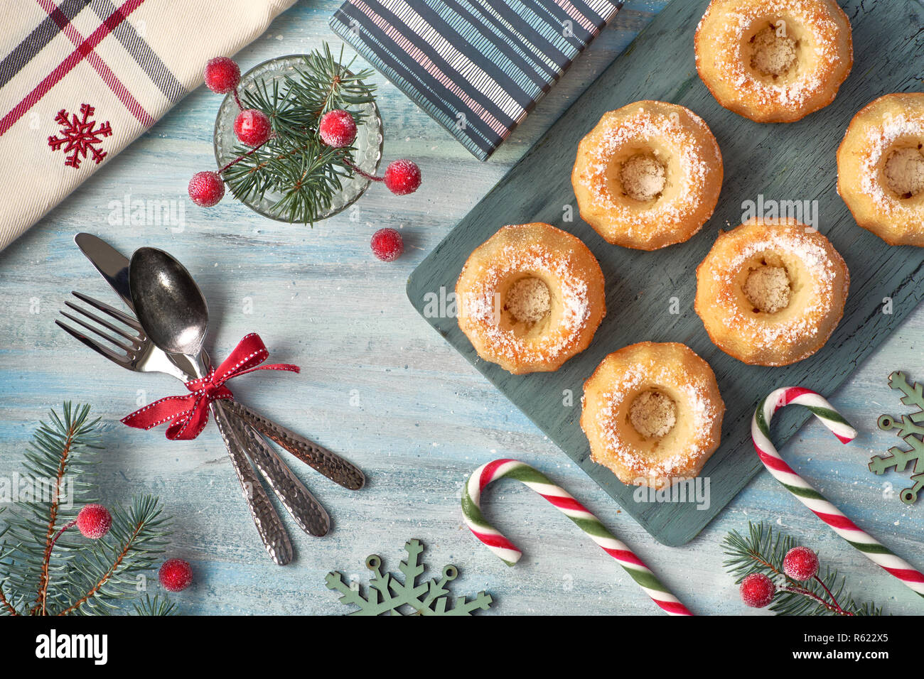 Mini anello bundt torte con lo zucchero a velo su sfondo chiaro con ramoscelli di abete, le bacche e le canne di caramella. Vacanze di Natale cibo dolce. Foto Stock