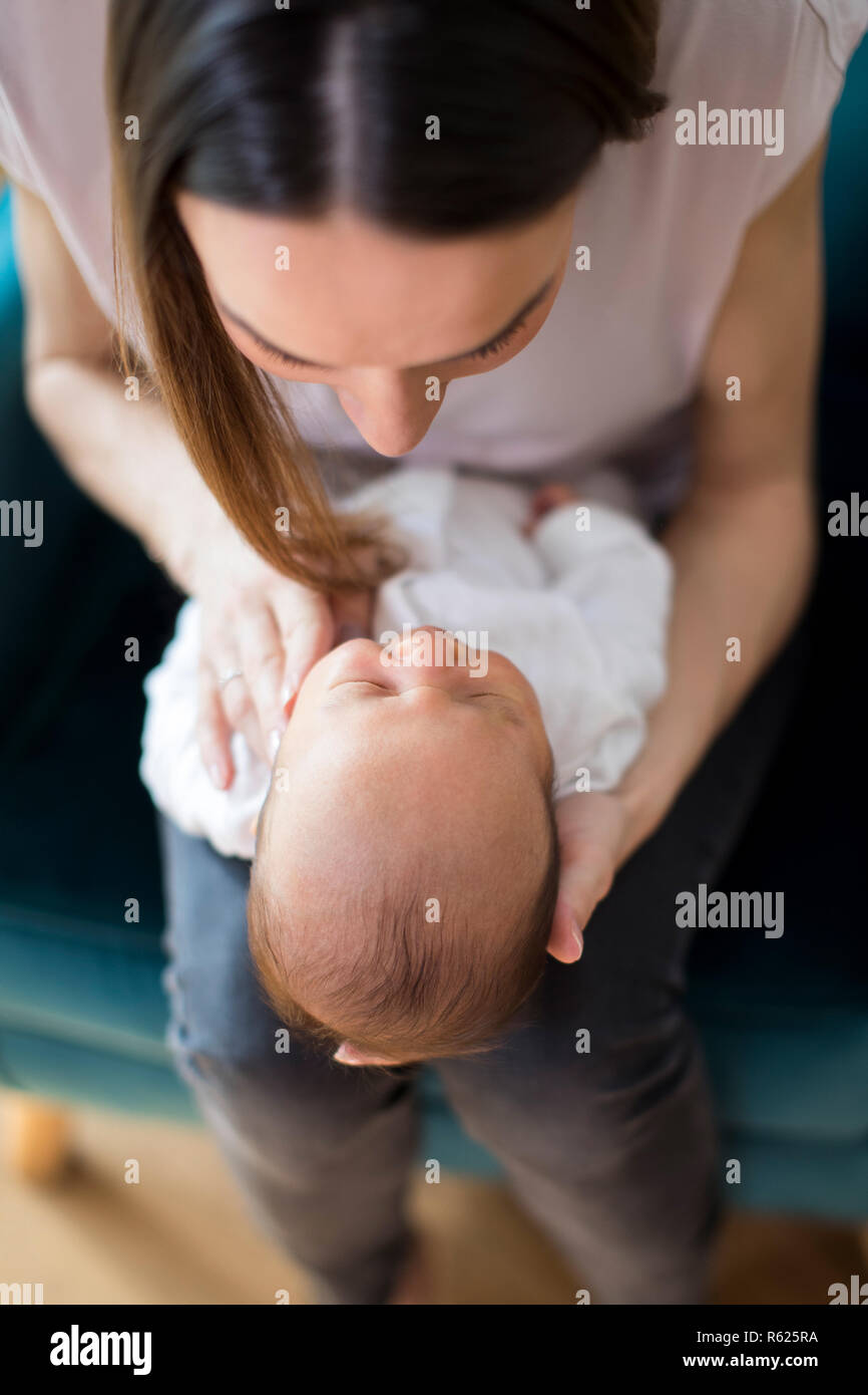 Vista aerea della madre Cuddling neonato figlio a casa Foto Stock